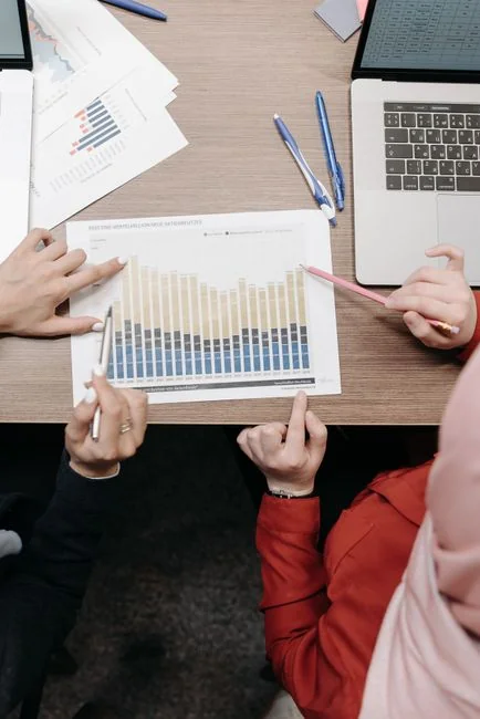 Un espace de travail moderne où des mains analysent des données marketing sur un ordinateur portable et des documents papier.
